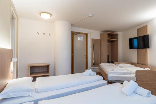 a room with three beds and a flat screen tv at Hotel Bella Italia Piancavallo in Piancavallo
