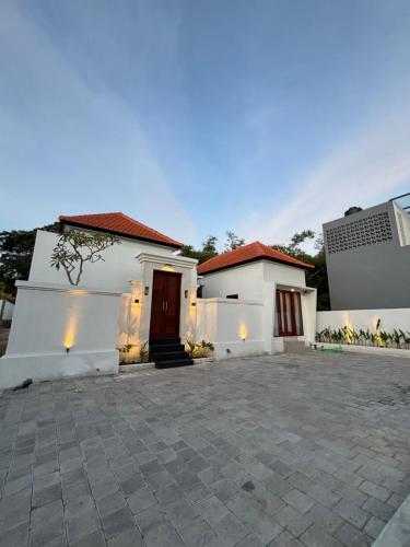 ein weißes Haus mit einer Auffahrt davor in der Unterkunft Amitha Lodge Uluwatu in Uluwatu