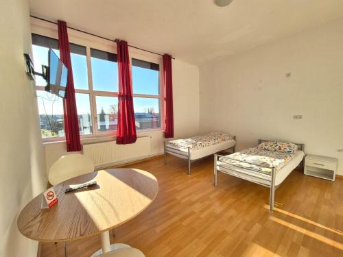 ein Zimmer mit zwei Betten und einem Tisch und einem Fenster in der Unterkunft GASTEM UG in Berlin
