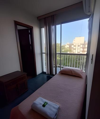 a hotel room with two beds and a large window at Cobertura com 4 quartos e ar condicionado in Cabo Frio
