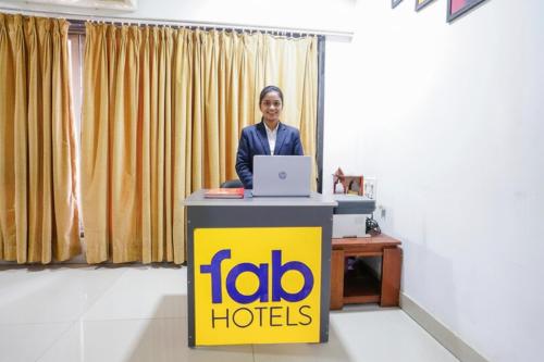 una mujer parada en una mesa con un portátil en FabHotel Rio House Apartment, en Bombay