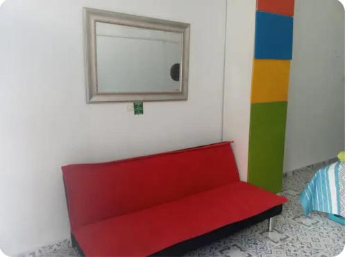 a red couch in a room with a mirror at BALLESTRINQUE - GETSEMANI- CARTAGENA DIVINa in Cartagena de Indias