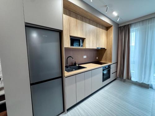 Una cocina con gabinetes blancos y un fregadero. en Airport dream - Modern, King size beds, en Someşeni