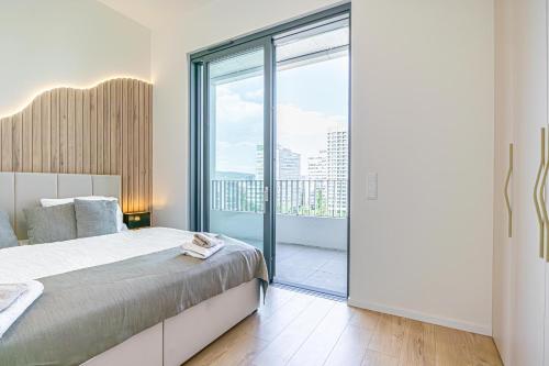 Un dormitorio con una cama y una ventana grande. en Fancy 2BR & 1LR Apartment Panoramic Sky View, en Nivy