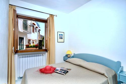 1 dormitorio con cama con libro y ventana en Maloon apt - 450m from the beach, en Isquia