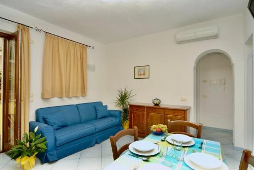 Una sala de estar con un sofá azul y una mesa. en Maloon apt - 450m from the beach, en Isquia