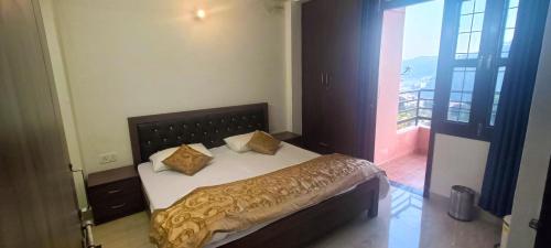 een bed in een slaapkamer met uitzicht op een balkon bij Mountain Breeze 2BHK with a spectacular view in Bhowāli