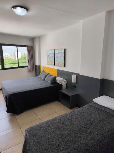 a hotel room with two beds and a window at Apart Hotel Alvear in Rosario