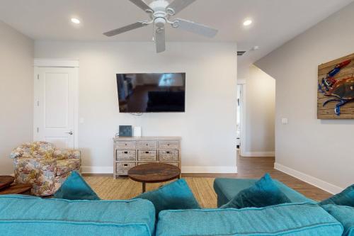 ein Wohnzimmer mit einem blauen Sofa und einem Deckenventilator in der Unterkunft The Wild Octopus at Palmilla Beach in Port Aransas