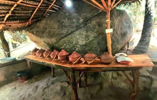 Una mesa de madera con ollas de barro encima. en Wooden Eco Cottage, en Katiyawa