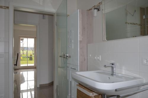 a white bathroom with a sink and a mirror at Ferienhaus zur Tulpe, Legoland in Ettenbeuren