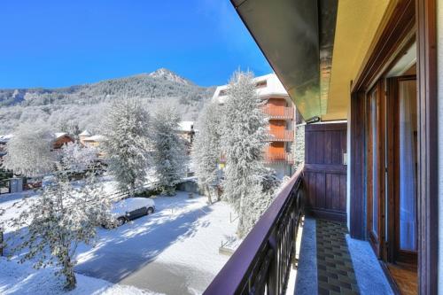 ein Balkon mit schneebedeckten Bäumen und einem Gebäude in der Unterkunft Il Nido di Elda few steps from skiing - Happy Rentals in Bardonecchia