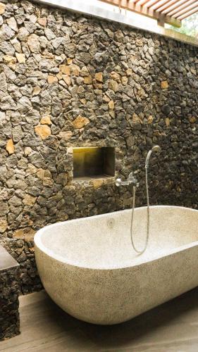 a stone bathroom with a tub in a stone wall at Villa Gubug Ijen Banyuwangi in Mantaak