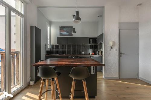 阿卡雄Arcachon Cœur de ville Appartement lumineux的厨房配有木台和2个酒吧凳