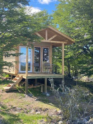 a small cabin with a deck in the woods at Cabaña Huemul in Villa Cerro Castillo