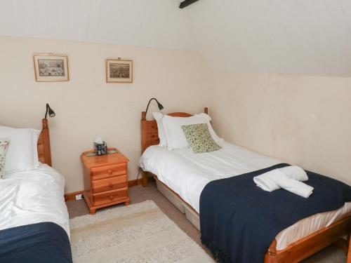 a bedroom with two beds and a night stand at Bridge Cottage in Budleigh Salterton