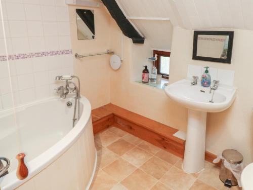 a bathroom with a sink and a bath tub at Bridge Cottage in Budleigh Salterton