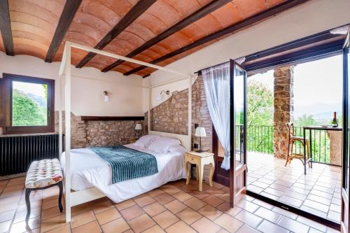 a bedroom with a bed and a balcony at Hotel Mas la Ferreria in La Vall de Bianya