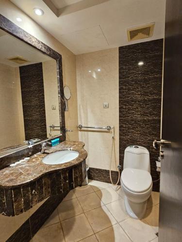 a bathroom with a toilet and a sink and a mirror at فندق وفاق صدقي in Al ‘Azīzīyah