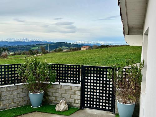 a fence with two potted plants and a view of mountains at Los Sauces de la Fuente in Santillana del Mar