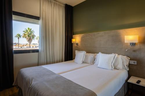 um quarto de hotel com uma cama grande e uma janela em Sevilla Green Suites em Alcalá de Guadaira