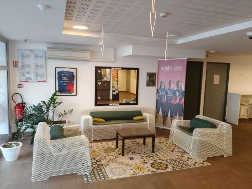 Una sala de estar con sillas, un sofá y una mesa. en Aparthotel Adagio Access Poitiers, en Poitiers