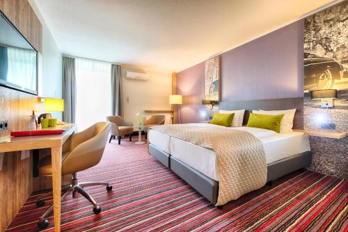 a hotel room with a bed and a desk at Leonardo Hotel Wolfsburg City Center in Wolfsburg
