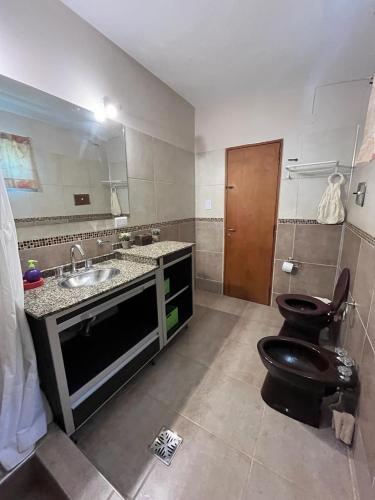 a bathroom with a black toilet and a sink at Casa Familiar Villa Carlos Paz in Villa Carlos Paz