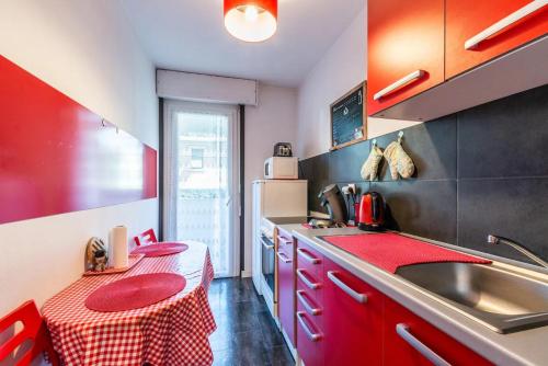 una cucina con armadi rossi, lavandino e tavolo di beau T1 30 résidence sécurisée proche centre ville parking privé wifi a La Celle-sous-Gouzon