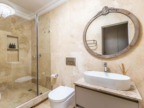 een badkamer met een toilet, een wastafel en een spiegel bij Marang Villa in Kaapstad