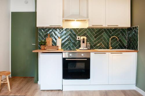 eine Küche mit weißen Schränken und einem schwarzen Backofen in der Unterkunft Le nid Briochin studio au coeur de Saint-Brieuc in Le Légué