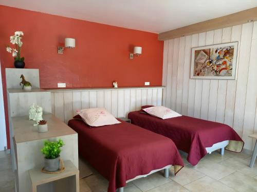 - 2 lits dans une chambre aux murs rouges dans l'établissement Gîte Harmony, à Châteauneuf-du-Rhône