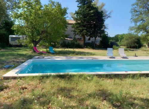 une piscine avec deux chaises et une maison dans l'établissement Gîte Harmony, à Châteauneuf-du-Rhône