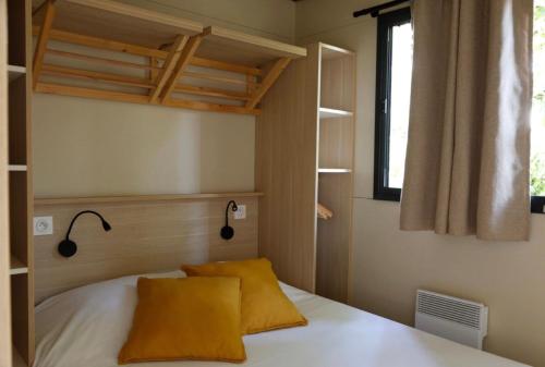a bedroom with a bed with two yellow pillows at Chalet 25m2 - Pierres Noires in Plouhinec