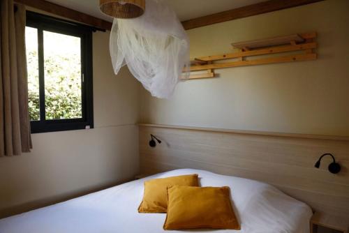 a bedroom with a bed with white sheets and a window at Chalet 20m2 - Sein in Plouhinec