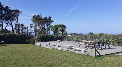a picnic table and benches in a field at Mobil-home Les volets rouges in Plouhinec