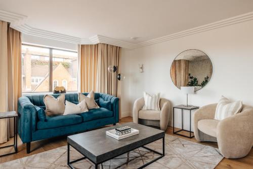 a living room with a blue couch and two chairs at The Eccleston by Nestor in London