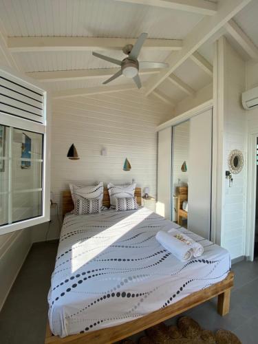 Un dormitorio con una cama grande con ventilador de techo. en Bungalow classé 2 étoiles avec jacuzzi et vue mer-Palbéa, en Schœlcher
