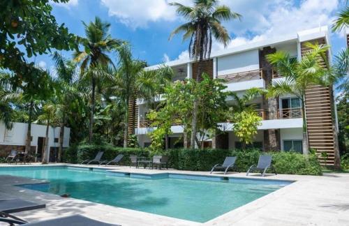 ein Swimmingpool vor einem Gebäude mit Palmen in der Unterkunft Paradise Found 3Bedroom Apartment with Pool in Las Terrenas