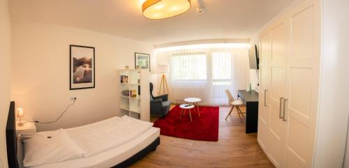 a bedroom with a white bed and a red rug at Hotel Quellenhof - Self-Check-in in Bad Urach