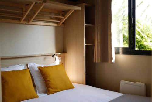 a bedroom with a bed with yellow pillows and a window at Chalet 35m2 - Armen in Plouhinec