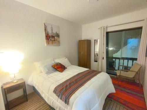 a bedroom with a large white bed and a window at Maruri Valentino apartment in Cusco