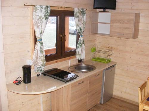 a kitchen with a counter with a sink and a window at Domki Kaja in Rewal