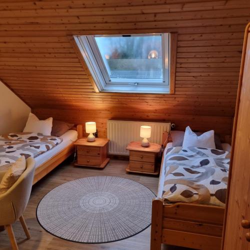 a attic room with two beds and a window at Gästezimmer Aschenbrenner in Bad Rodach