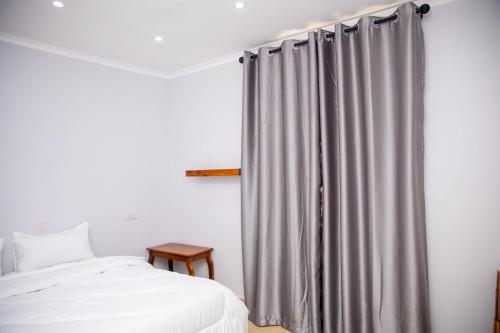 a bedroom with a bed and a gray curtain at Salt Garden Inn in Dar es Salaam