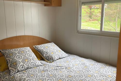 een slaapkamer met een bed met twee kussens en een raam bij Chalet Bungalow 2 Chambres 56 in LʼEstréchure