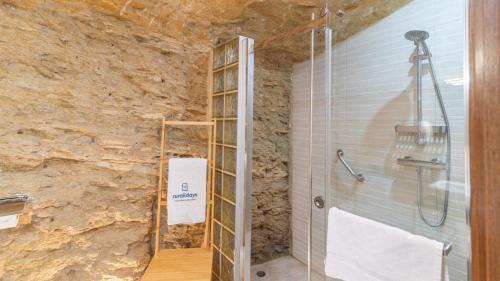 a shower in a bathroom with a stone wall at Cueva El Arrabal Setenil by Ruralidays in Setenil