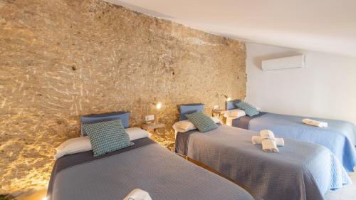 three beds in a room with a stone wall at Cueva El Arrabal Setenil by Ruralidays in Setenil