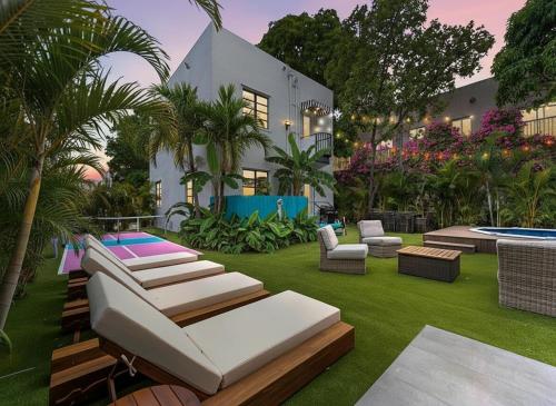 a garden with lounge chairs and a house at Villa mi Amor Walkable Pool & Games in Miami