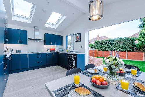 3 Bedroom Free Parking Hale Home في هييل: مطبخ به دواليب زرقاء وطاولة عليها فاكهة